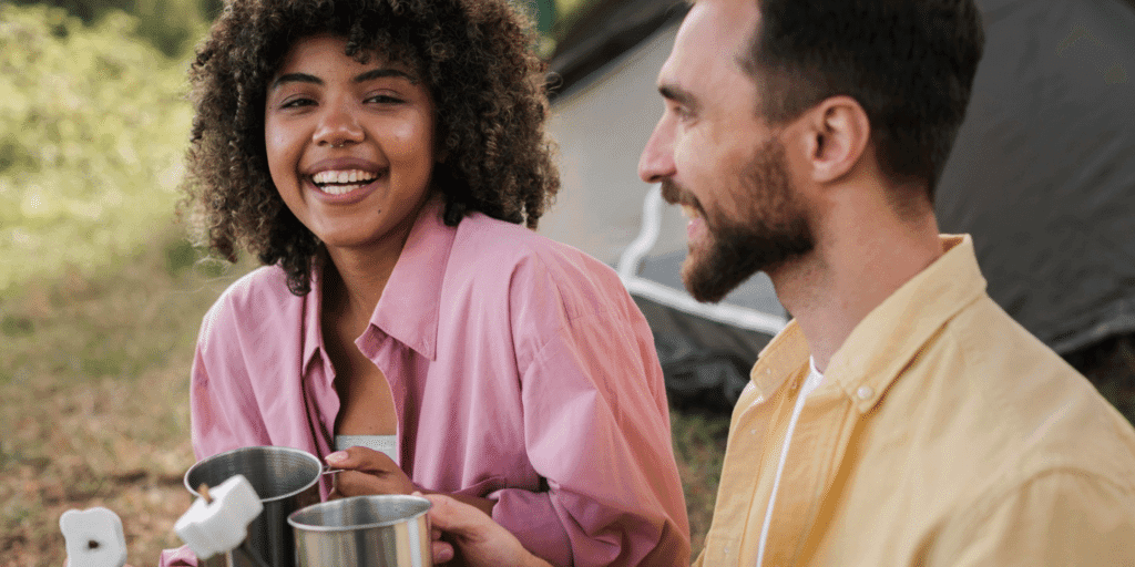Are Situationships Toxic? A male and female couple laugh over roasting marshmallows over a campfire while camping.