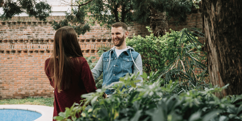 A couple laughing by a backyard pool illustrat that it's important to act natural when approaching a girl and try not to be too aggressive.
