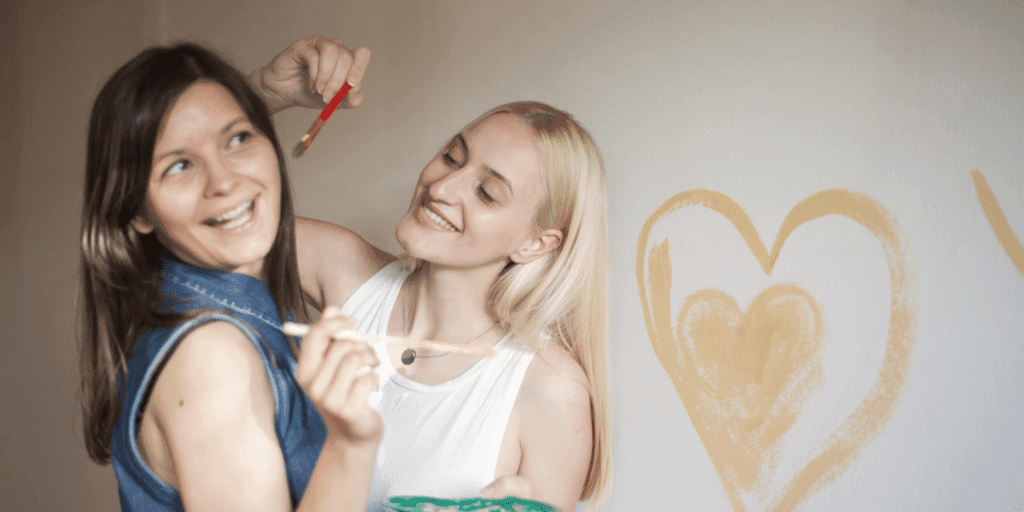 Two women painting and laughing.