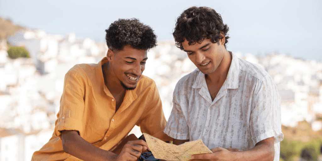 A male couple read a map while traveling together on a dating getaway.